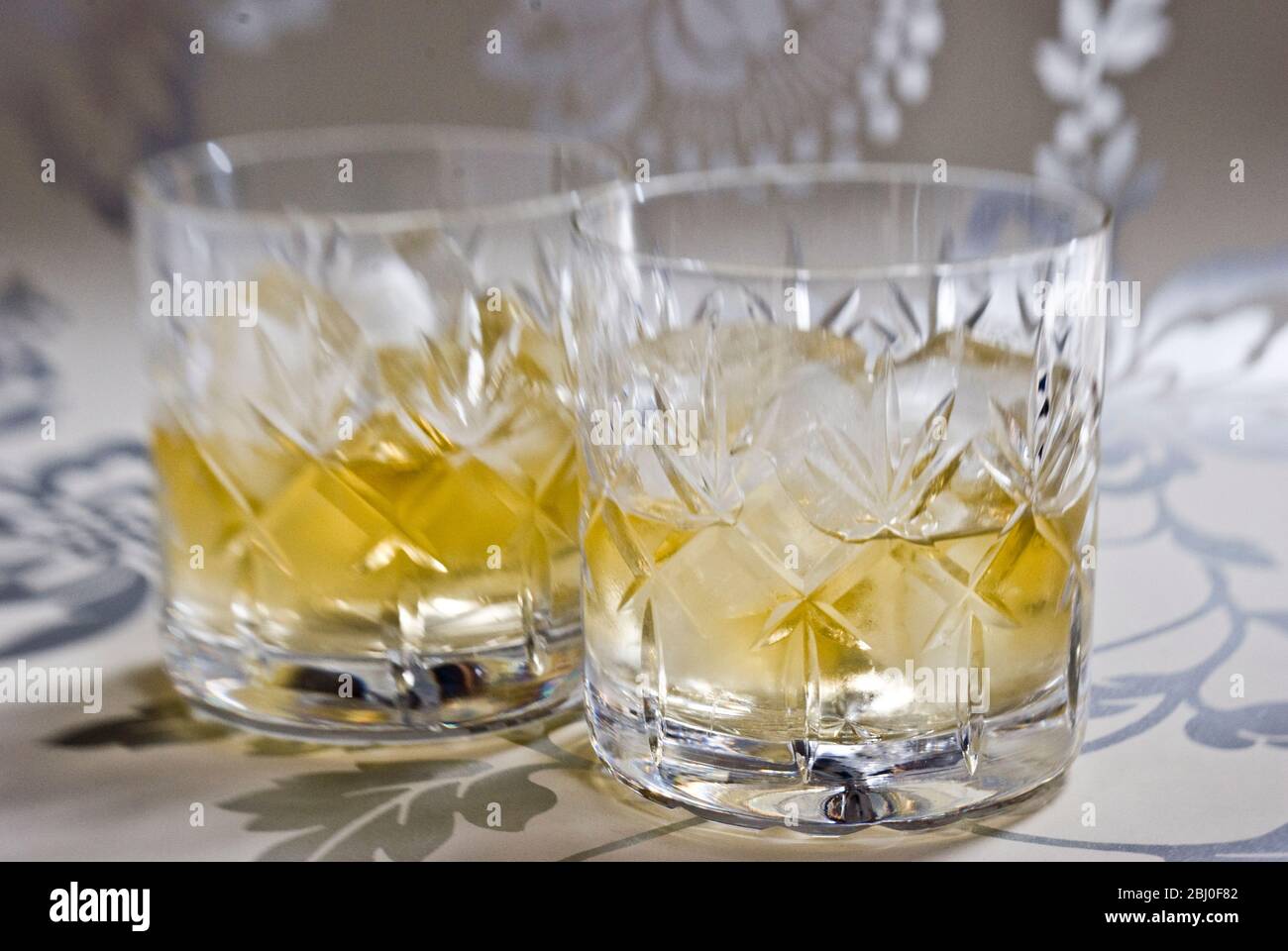 Scotch Whisky auf Eis in geschliffenem Bleikristall auf dekorativer Silberoberfläche - Stockfoto