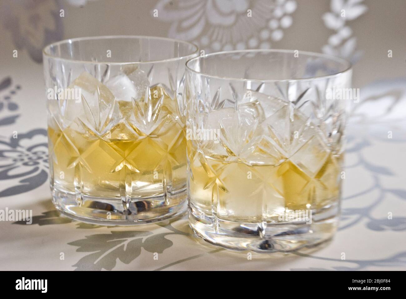 Scotch Whisky auf Eis in geschliffenem Bleikristall auf dekorativer Silberoberfläche - Stockfoto