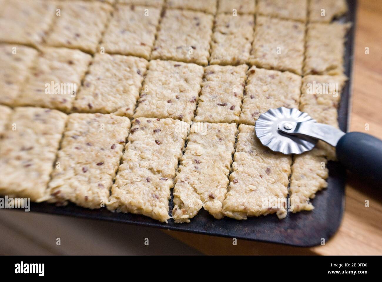 Ausstechteig auf Backblech ausgerollt, mit Teigmesser geschnitten, bevor er in den Ofen geht - Stockfoto