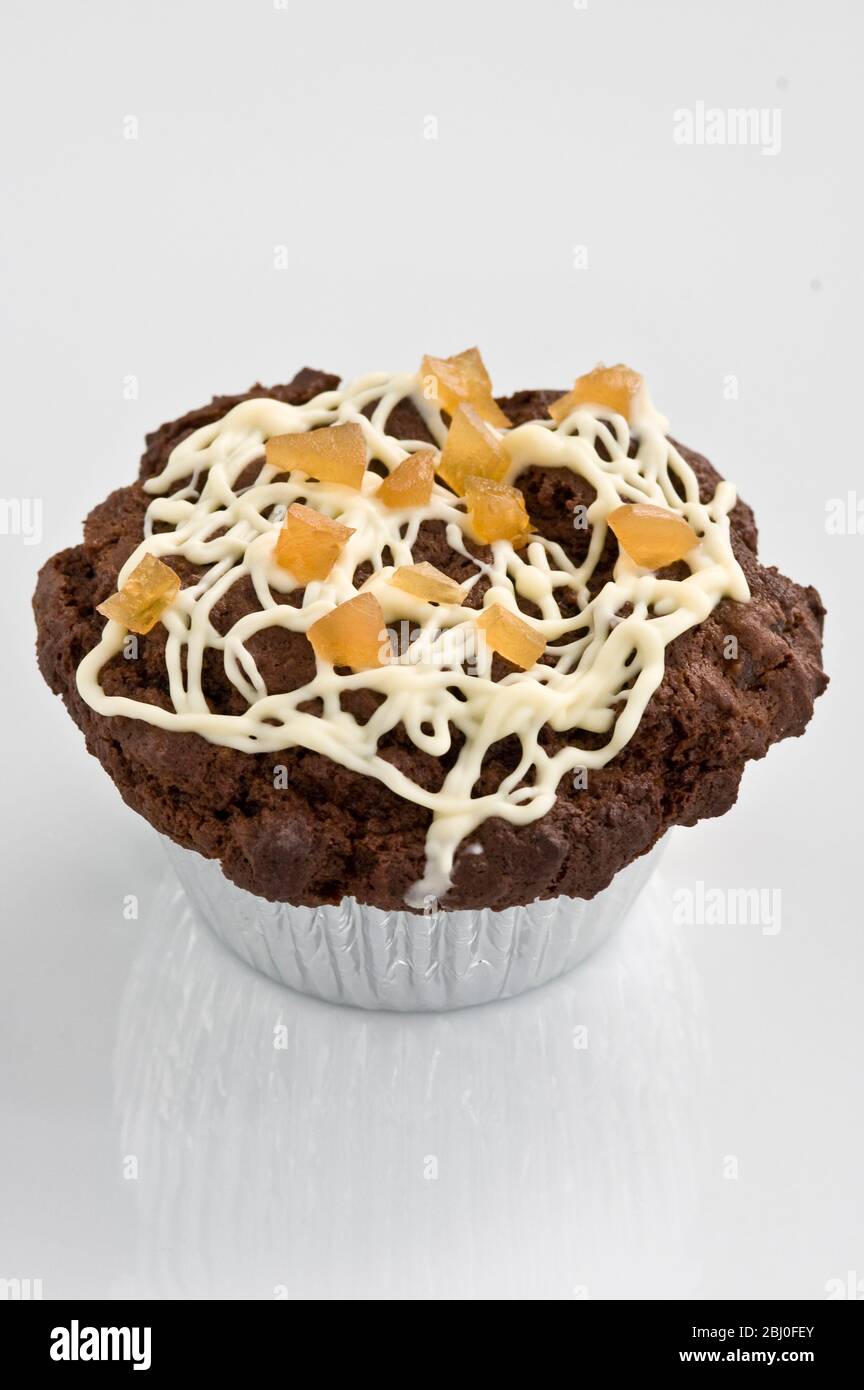 Schokoladenmuffin mit beträufelten Glasur mit getrockneten Mangostücken verziert - Stockfoto