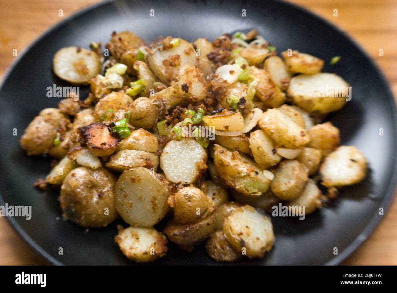 Gericht mit gebratenen Kartoffeln, mit Sardellen, Frühlingszwiebeln und Semmelbröseln anbraten. - Stockfoto