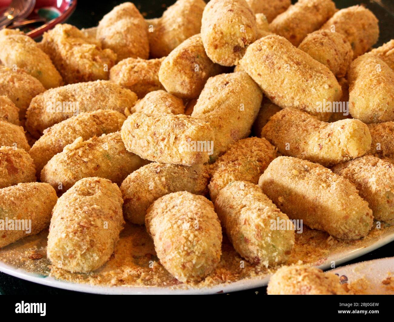 Teller voll mit frisch zubereiteten Kartoffelkroketten. Zu Kartoffelbrei werden Milch, Salz, Pfeffer, gehackte Zwiebel, geschlagenes Eigelb und Mehl hinzugefügt. Sie sind Chi Stockfoto