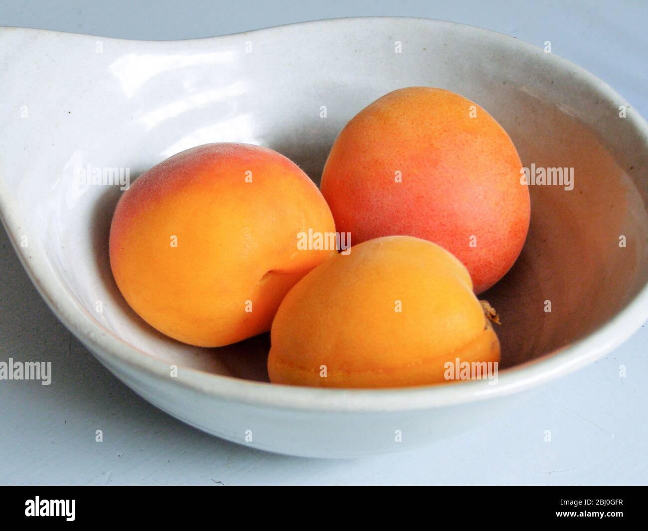 Frische, ganze Aprikosen, in kleiner Keramikschale - Stockfoto