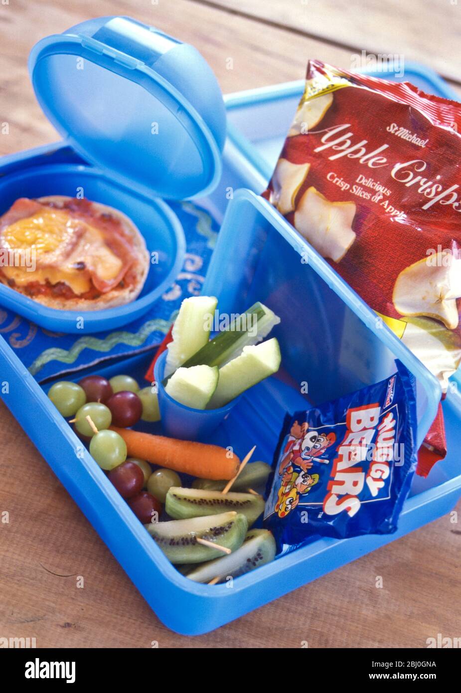 Kinderpackung Mittagessen mit frischen, rohen, Gemüse, Pizzarollen und Apfelchips, in blauen Kunststoffboxen - Stockfoto