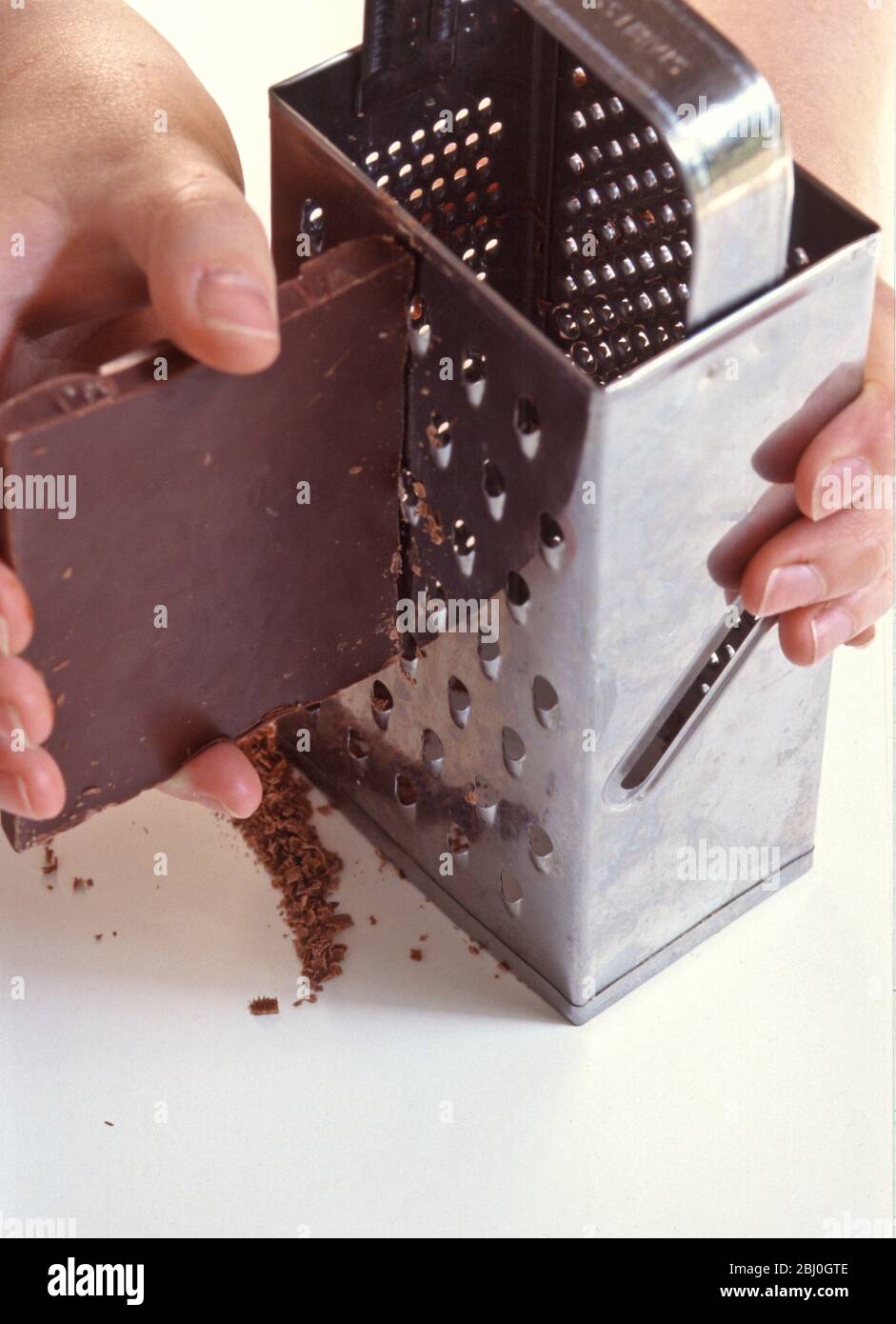 Reibe Block von dunkler Schokolade auf Chrom Reibe. - Stockfoto