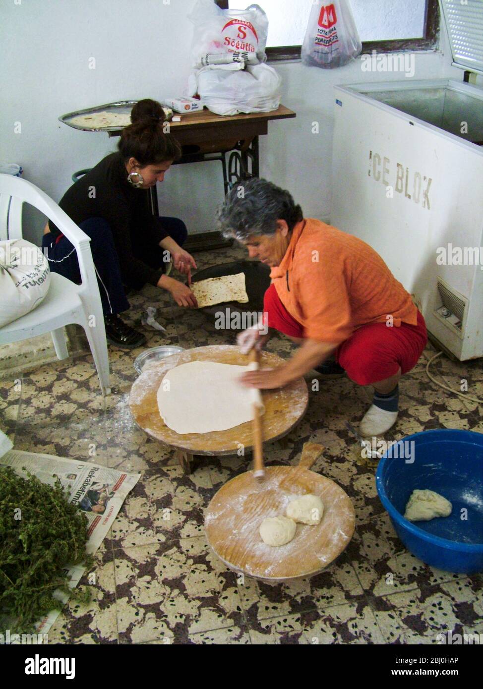 Türkische Frau Bäcker Rollen große dünne Kreise von Brot auf einem runden Holzbrett auf dem Boden der Kai Bäckerei. Hinter ihr steht die gasgefeuerte Heizplatte Stockfoto