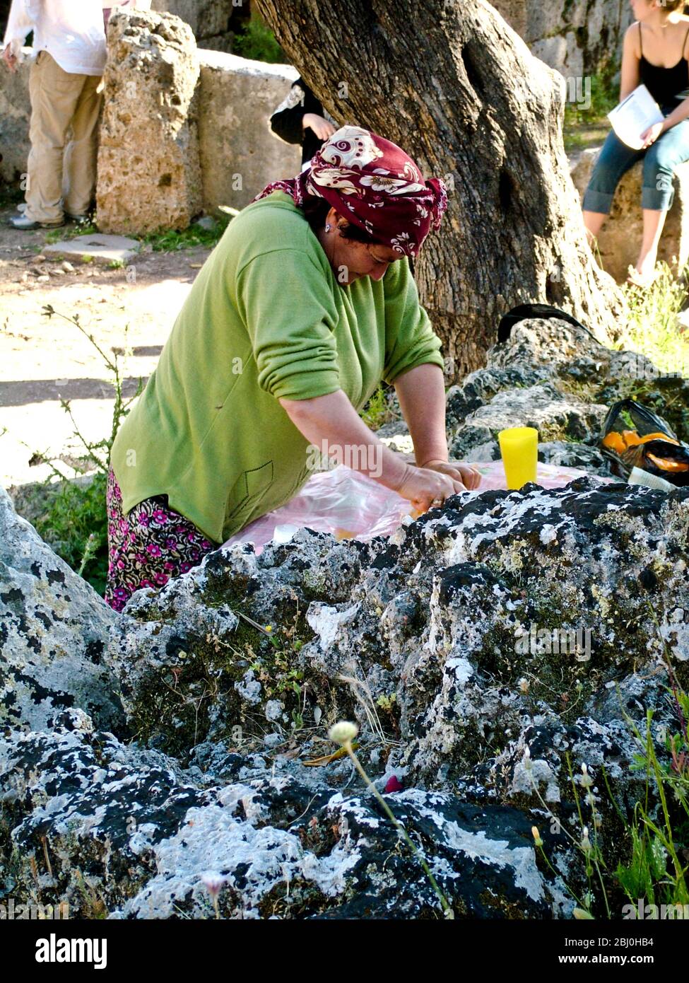 Frau quetscht Orangen, um Gläser mit frischem Saft an Touristen im antiken griechischen Amphitheater im Süden der Türkei zu verkaufen - Stockfoto