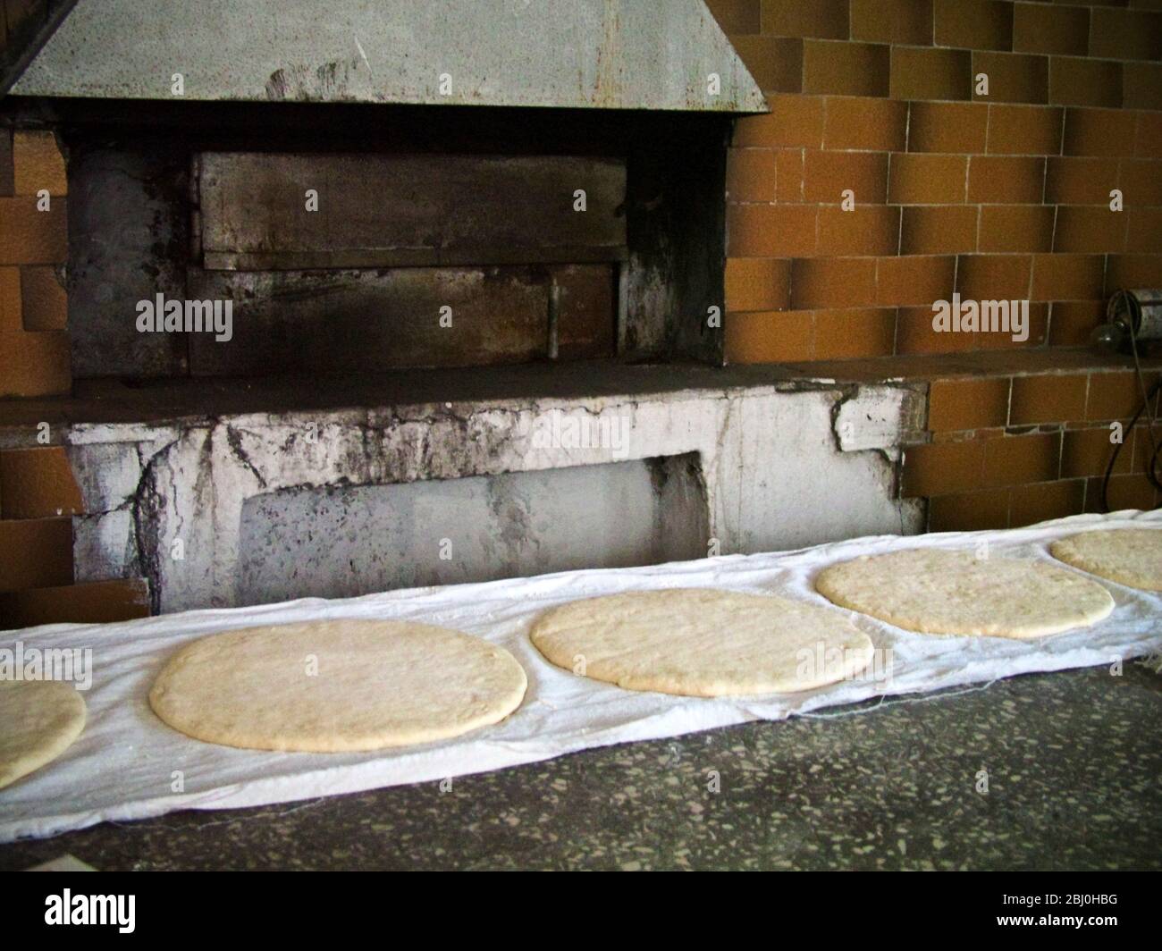 Große runde flache Brote, die auf sauberen Tüchern auf der Theke der Bäckerei am Kai in Selimiye, an der Südküste Anatoliens, Türkei aufsteigen - Stockfoto