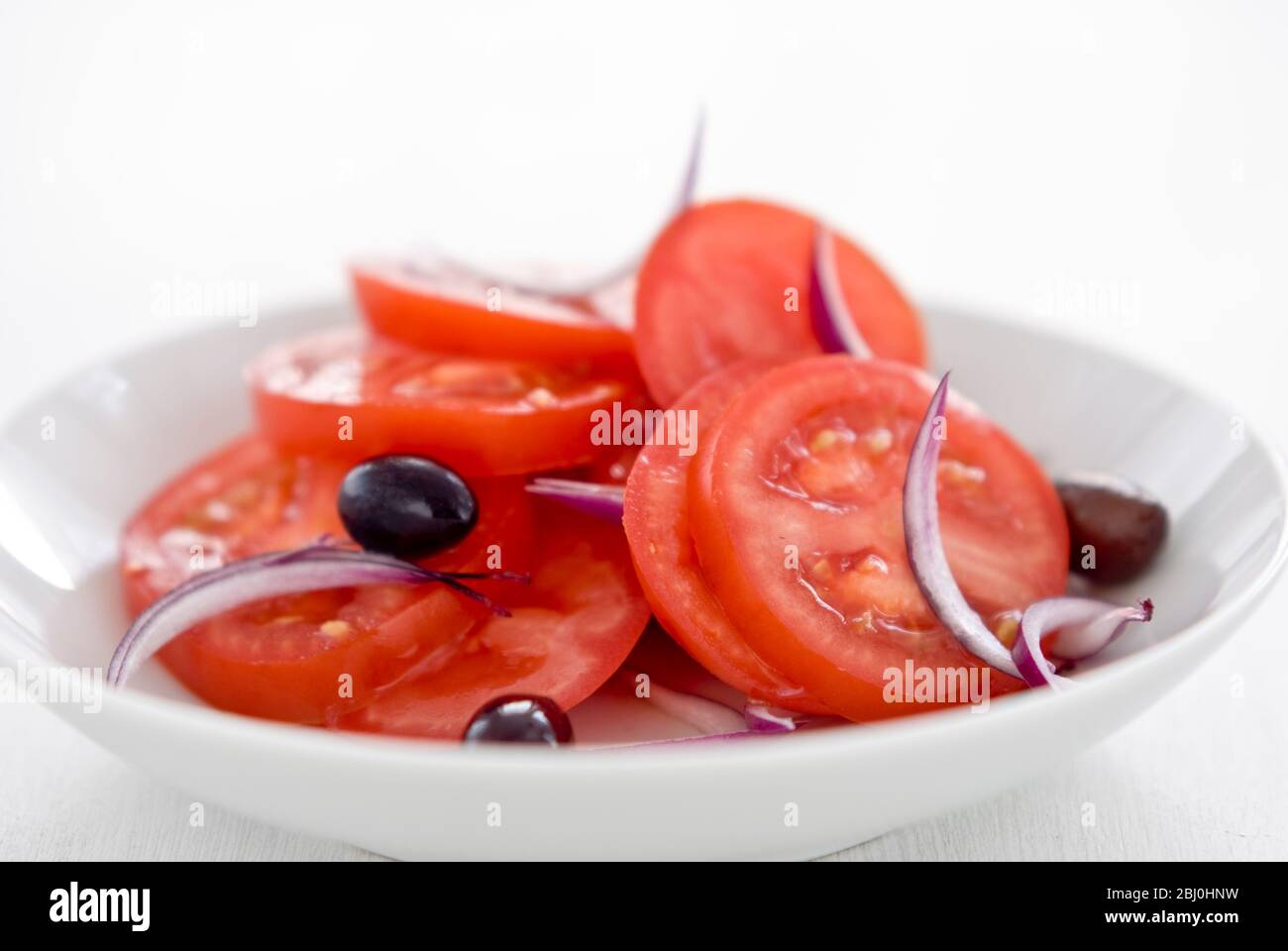 Tomatensalat mit roten Zwiebeln und schwarzen Oliven - Stockfoto