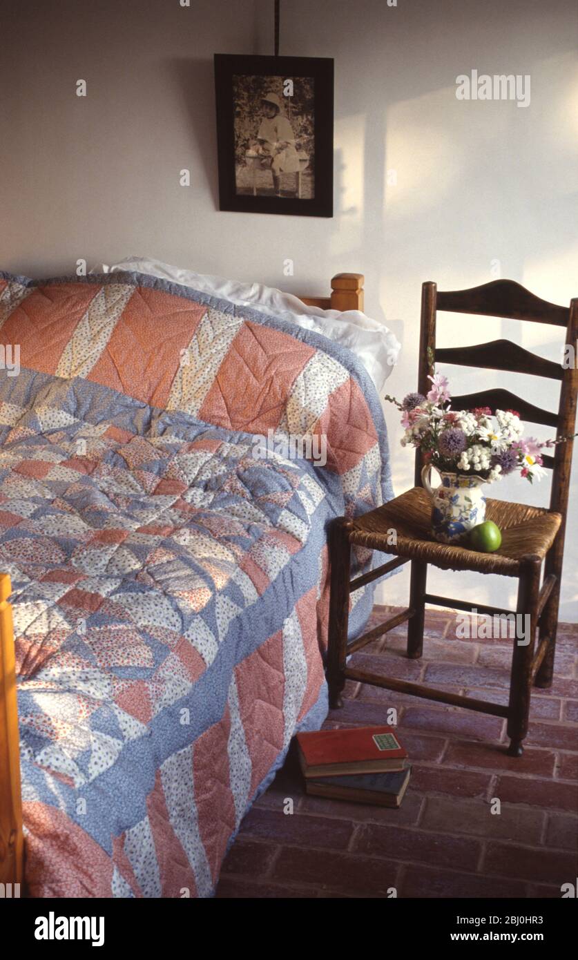 Cottage Schlafzimmer mit Büchern und Blumen und alten Sessel. - Stockfoto