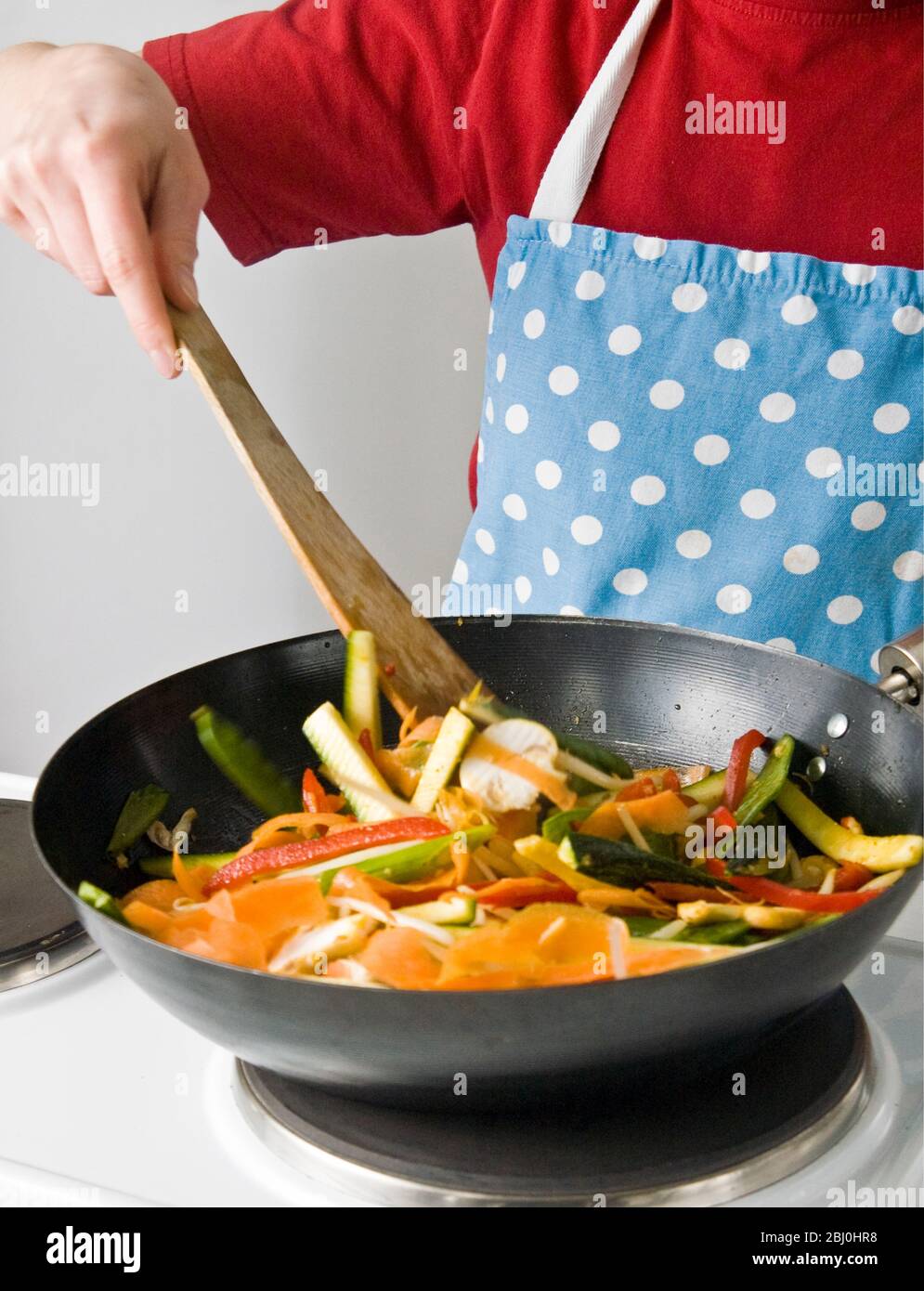 Kochen für Kinder - dünnt geschnittenes Gemüse in einer Wok-Pfanne mit Antihaftbeschichtung. - Stockfoto