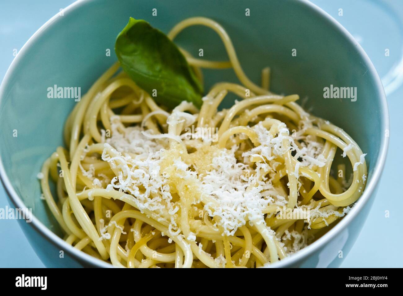 Schale mit Spaghetti mit Olivenöl und frisch geriebenem Parmesan in Seladonschüssel - Stockfoto