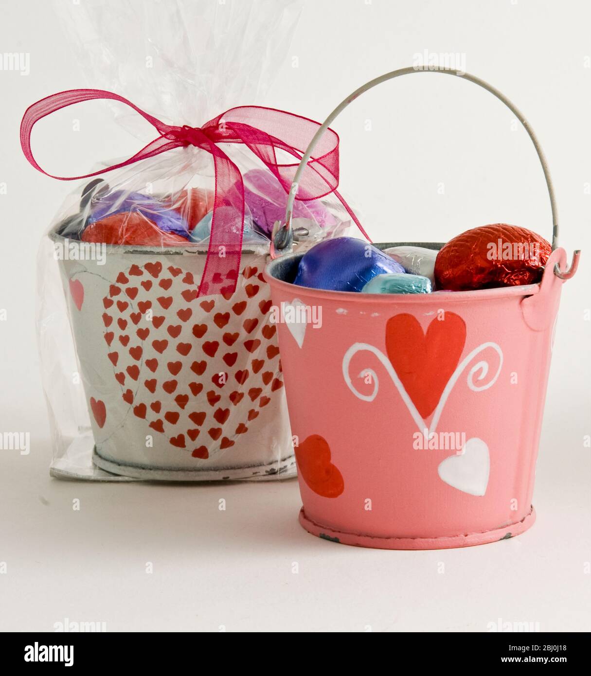 Kleine Eimer, dekorativ bemalt mit Herzen, gefüllt mit Pralinen als Valentinstag Geschenke, - Stockfoto