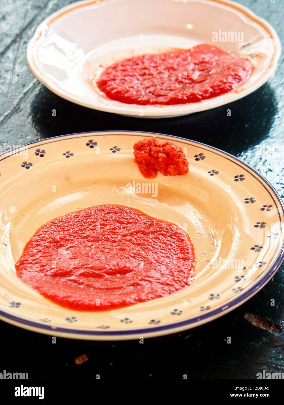 Zwei Sorten Tomatenmark - Passata und Passata Rustico auf italienischen Tellern - Stockfoto