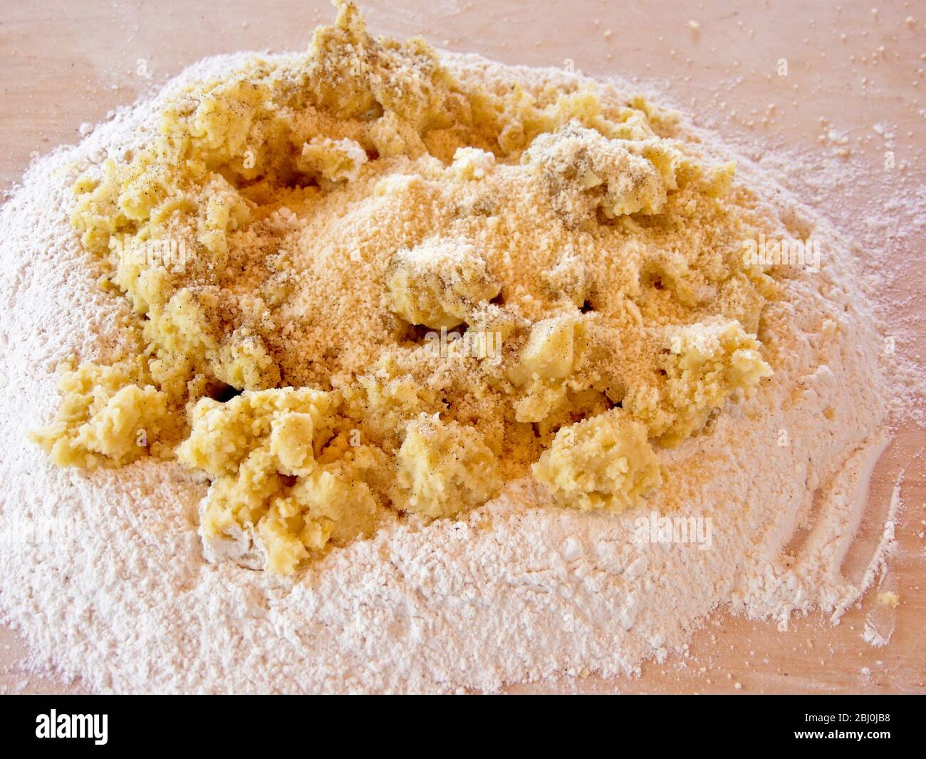 Vermischen von gepressten Kartoffeln und gradierten Parmesan in Mehl für die Herstellung von Gnocchi. Stockfoto