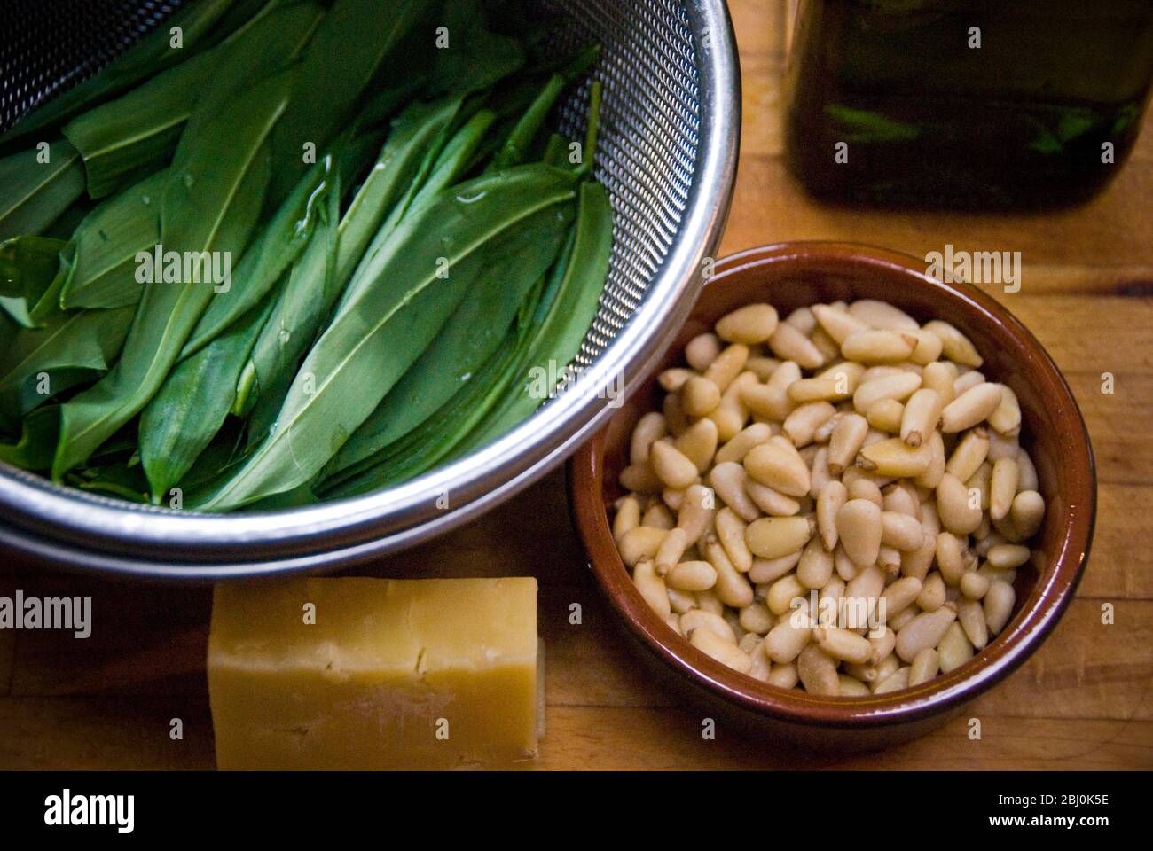 Zutaten für Bärlauch-Pesto, gewaschene Bärlauch-Blätter, Pinenuts in kleiner Schüssel und reifen Cheddar-Käse. Aufgenommen mit Lensbaby-Objektiv für verschwommene Aufnahmen Stockfoto
