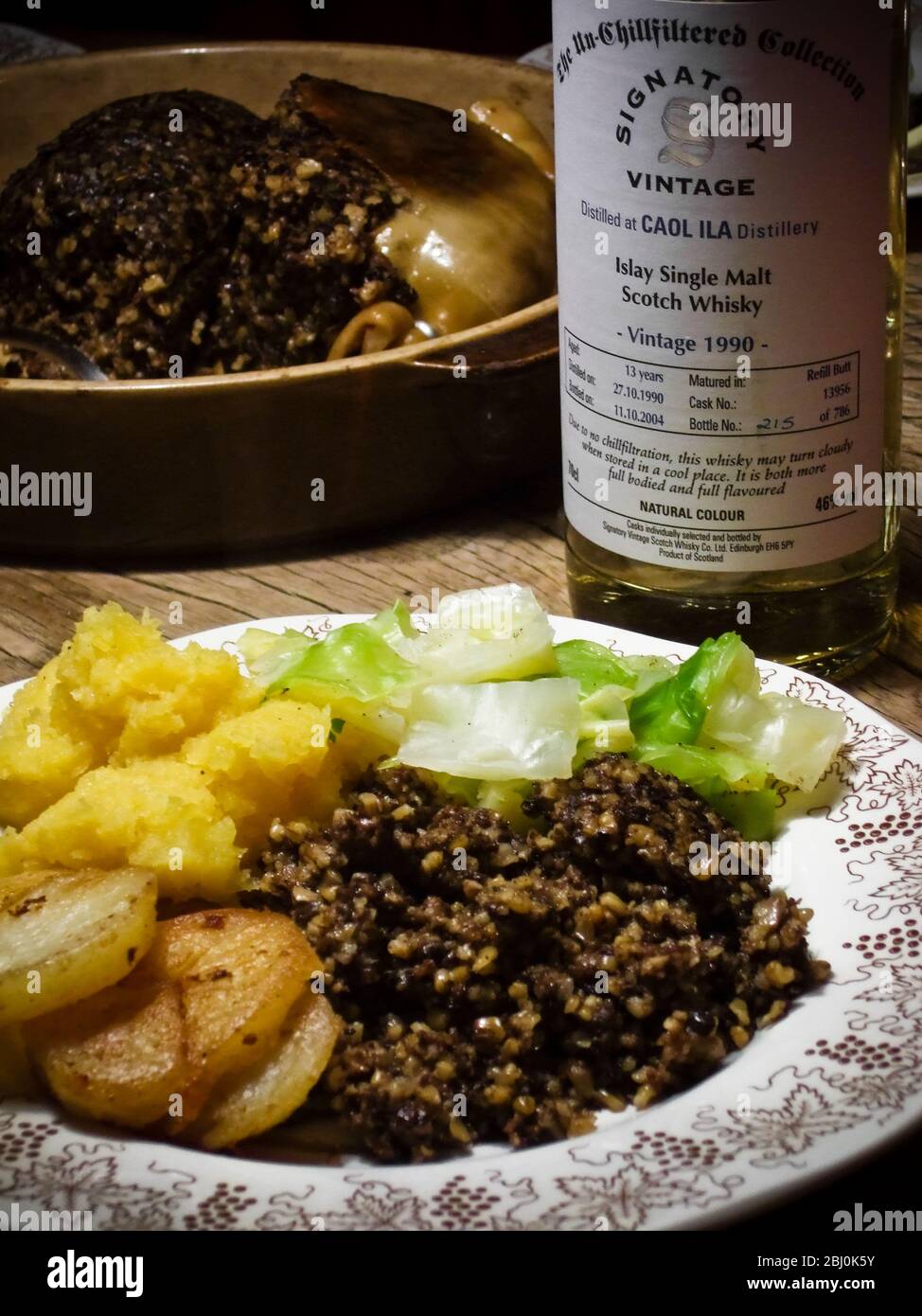 Haggis mit erstklassigem Whisky für Burns Night, serviert mit traditioneller Begleitung von "Bashed Neeps" (pürierter schwede), aber mit Zusatz von sautiertem p Stockfoto