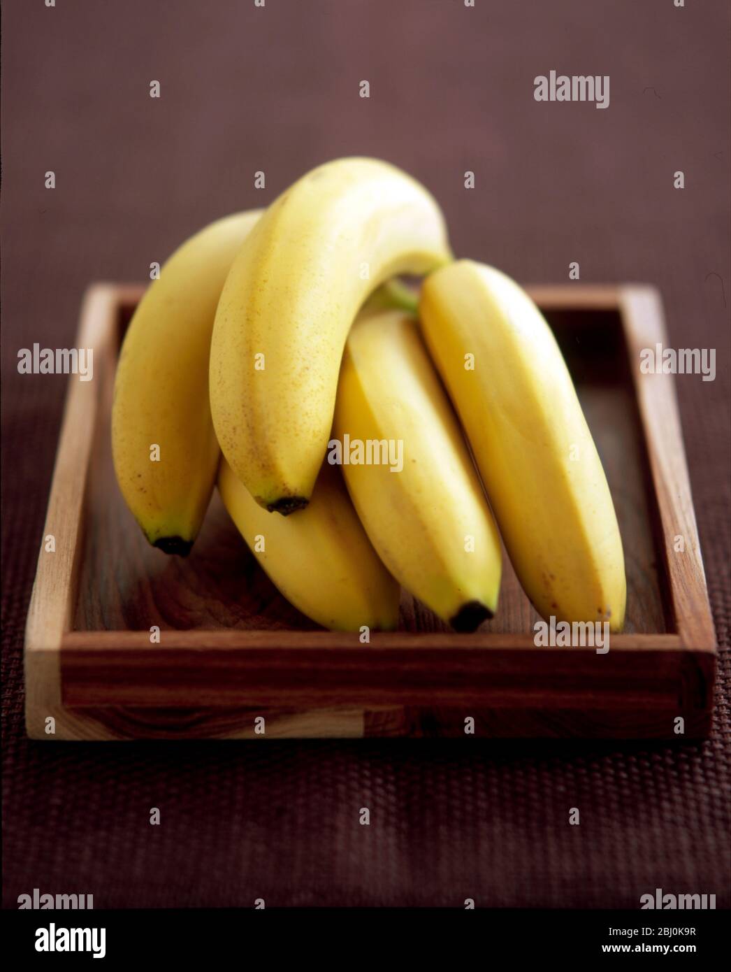 Hand' von Bananen auf Holztablett - Stockfoto