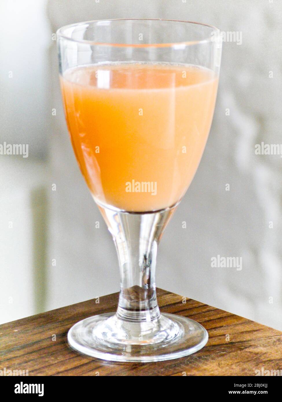 Grapefruitsaft in Glas auf Ecke des Tisches - Stockfoto