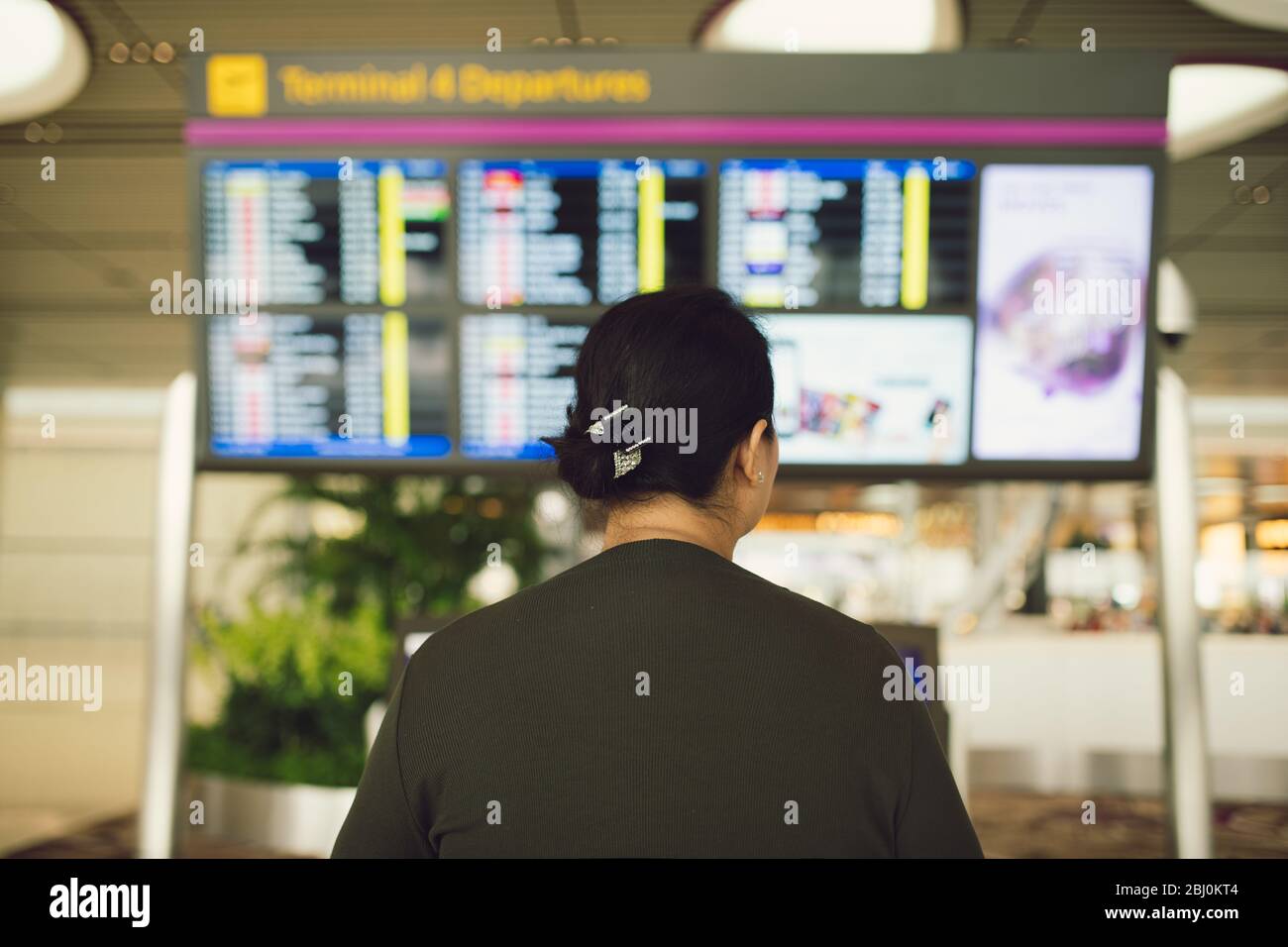 Passagiere, die am Fluginformationsbrett im Wartebereich des Flughafenterminals reisen, prüfen die Zeit für Abflug-Ankunft und den Flugstatus für Verspätungen Stockfoto