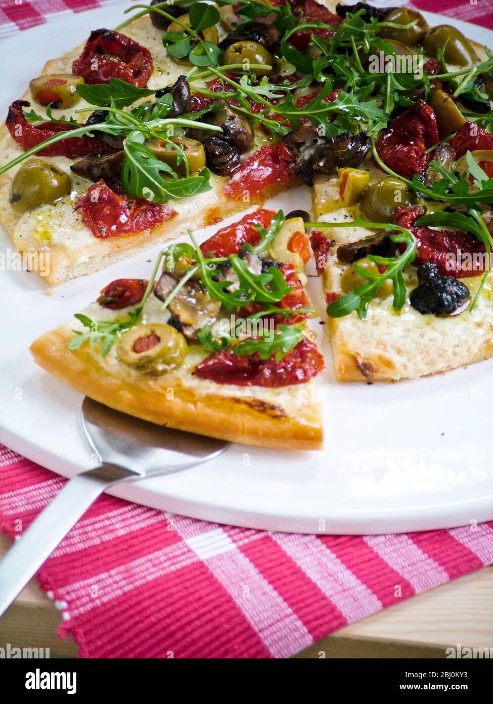 Pizza mit allerlei Tomaten, Aubergine, Oliven, Mozzarella und Rucola - Stockfoto