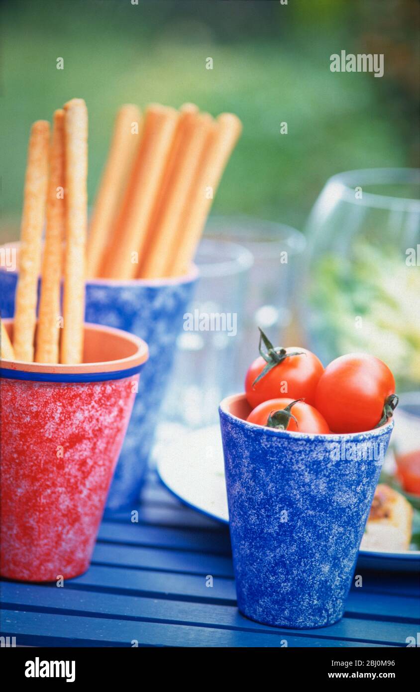 Brotstangen und Tomaten auf dem Partytisch im Freien - Stockfoto