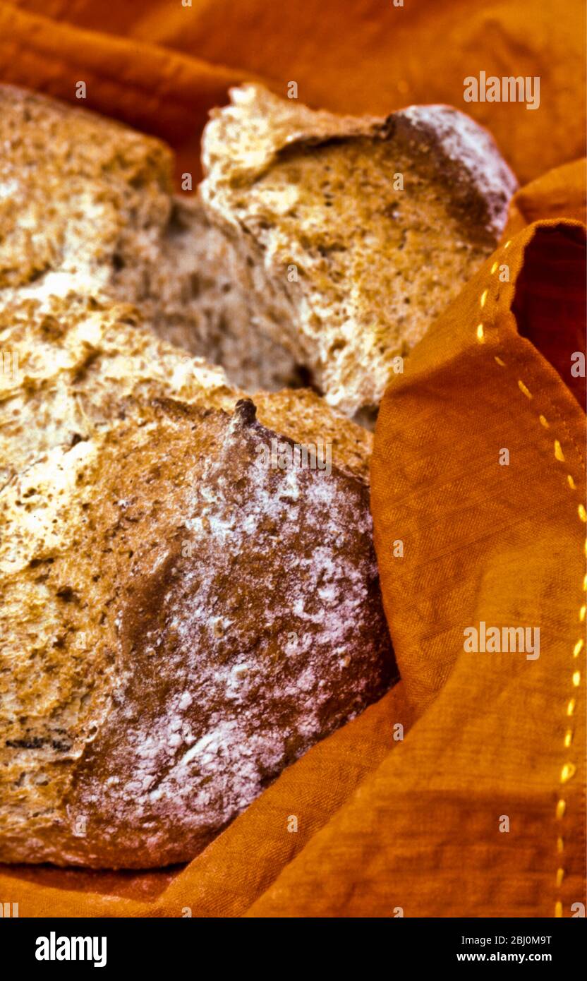 Knuspriges braunes Brot in orangefarbener Serviette - Stockfoto