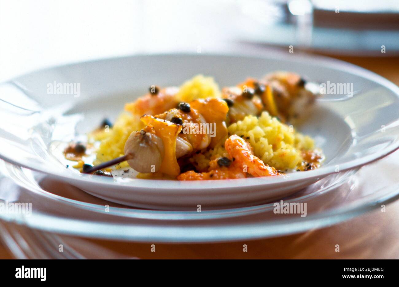 Kebab von Fisch, Schalotten und gekochten gelben Paprikastücken auf Safranreis - Stockfoto