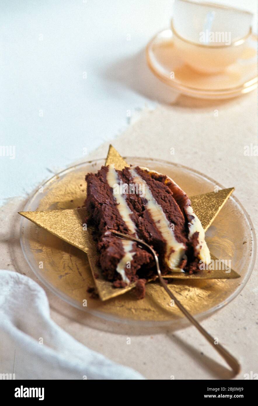 Reichhaltige Schokoladenkuchen mit Buttercreme-Schichten auf sternförmigen Teller mit Dessertgabel serviert - Stockfoto