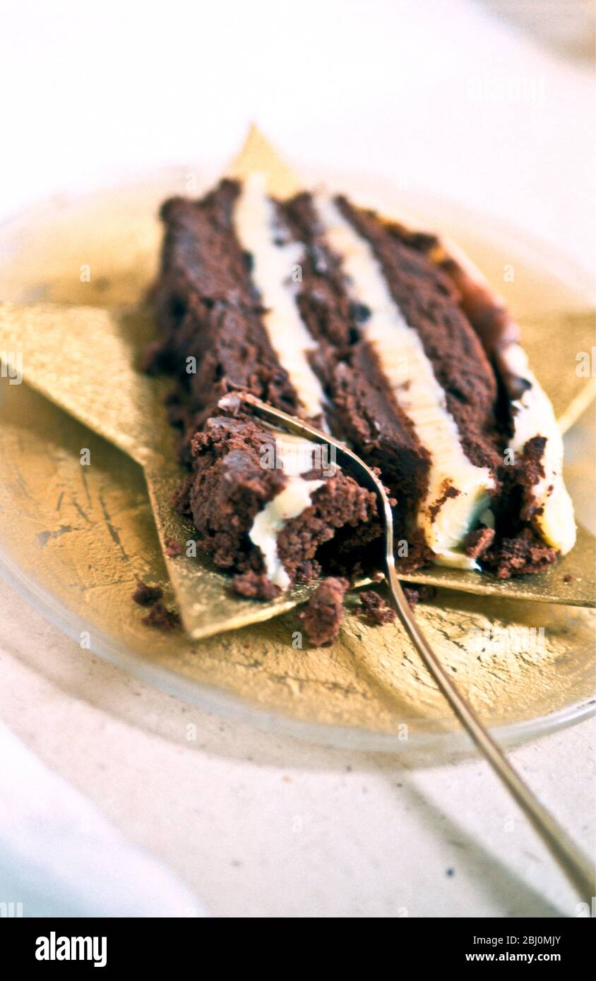 Reichhaltige Schokoladenkuchen mit Schichten von Buttercreme auf sternförmigen Teller mit Dessertgabel serviert - Stockfoto
