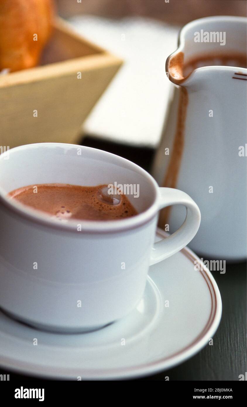 Krug und Tasse heiße Trinkschokolade, auf französischem Cafétisch - Stockfoto