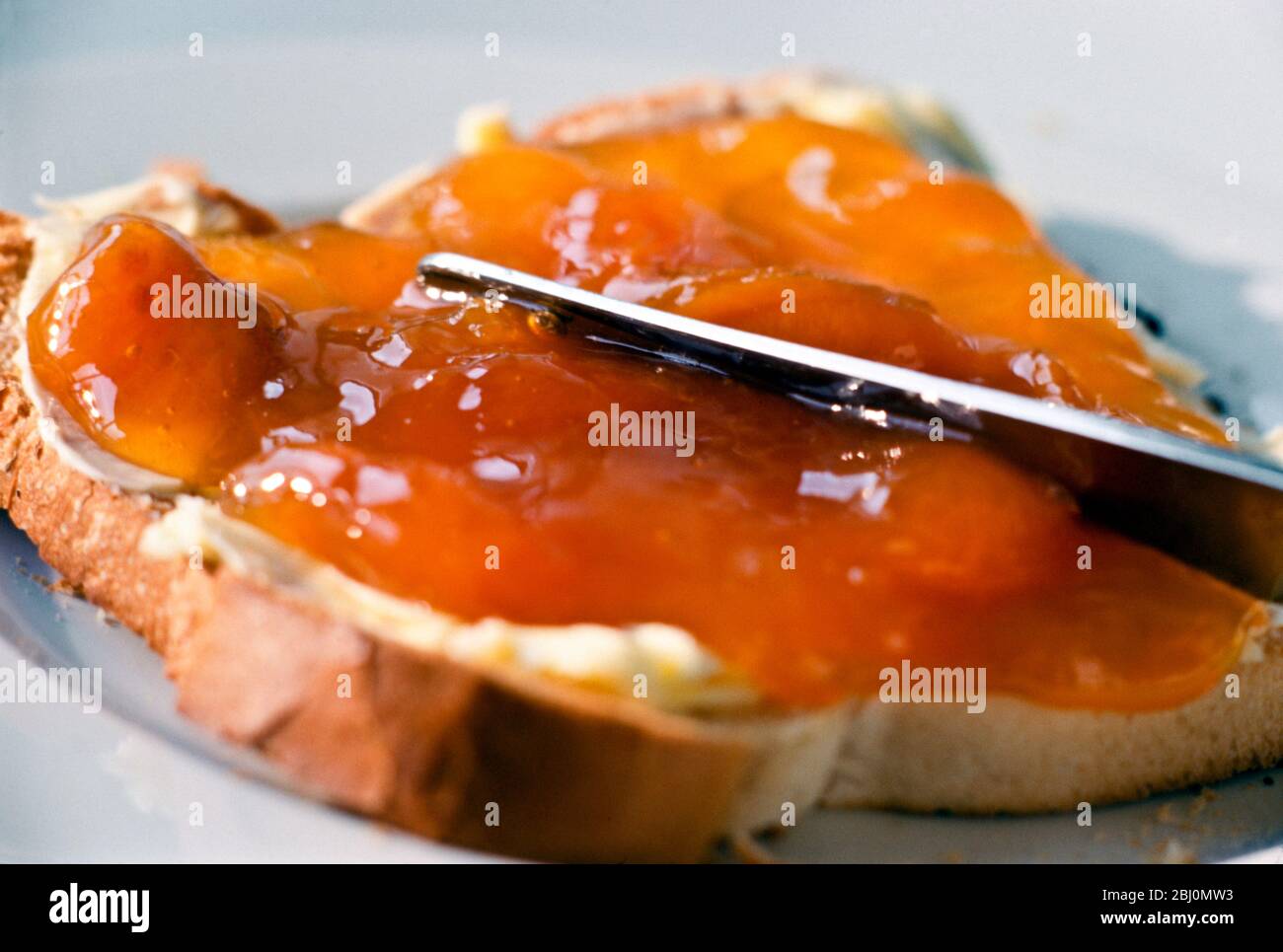 Aprikosenmarmelade, dick auf gebuttertem Toast verteilt - Stockfoto
