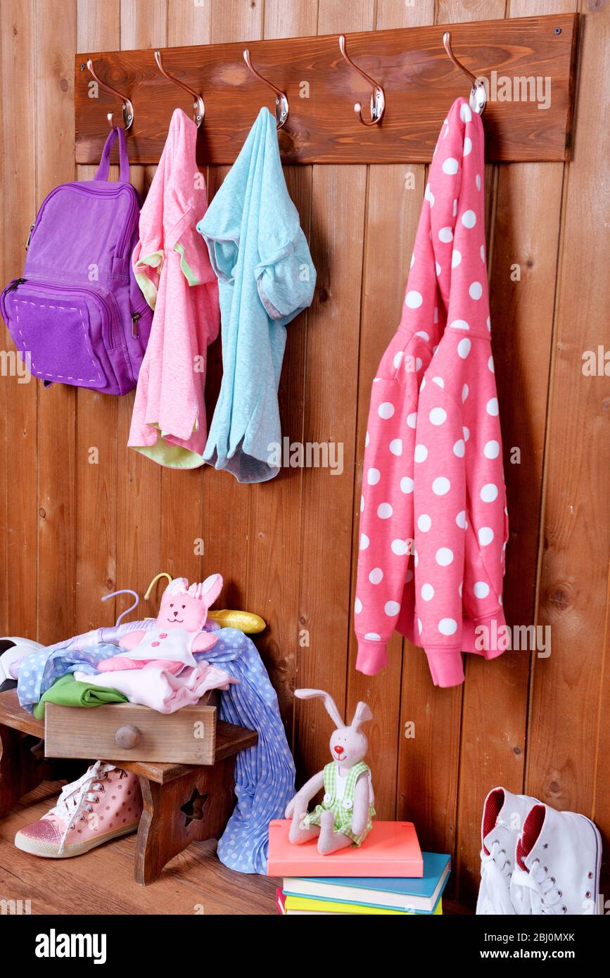Kindersachen hängen an der Wand und stapeln sich im Zimmer Stockfoto