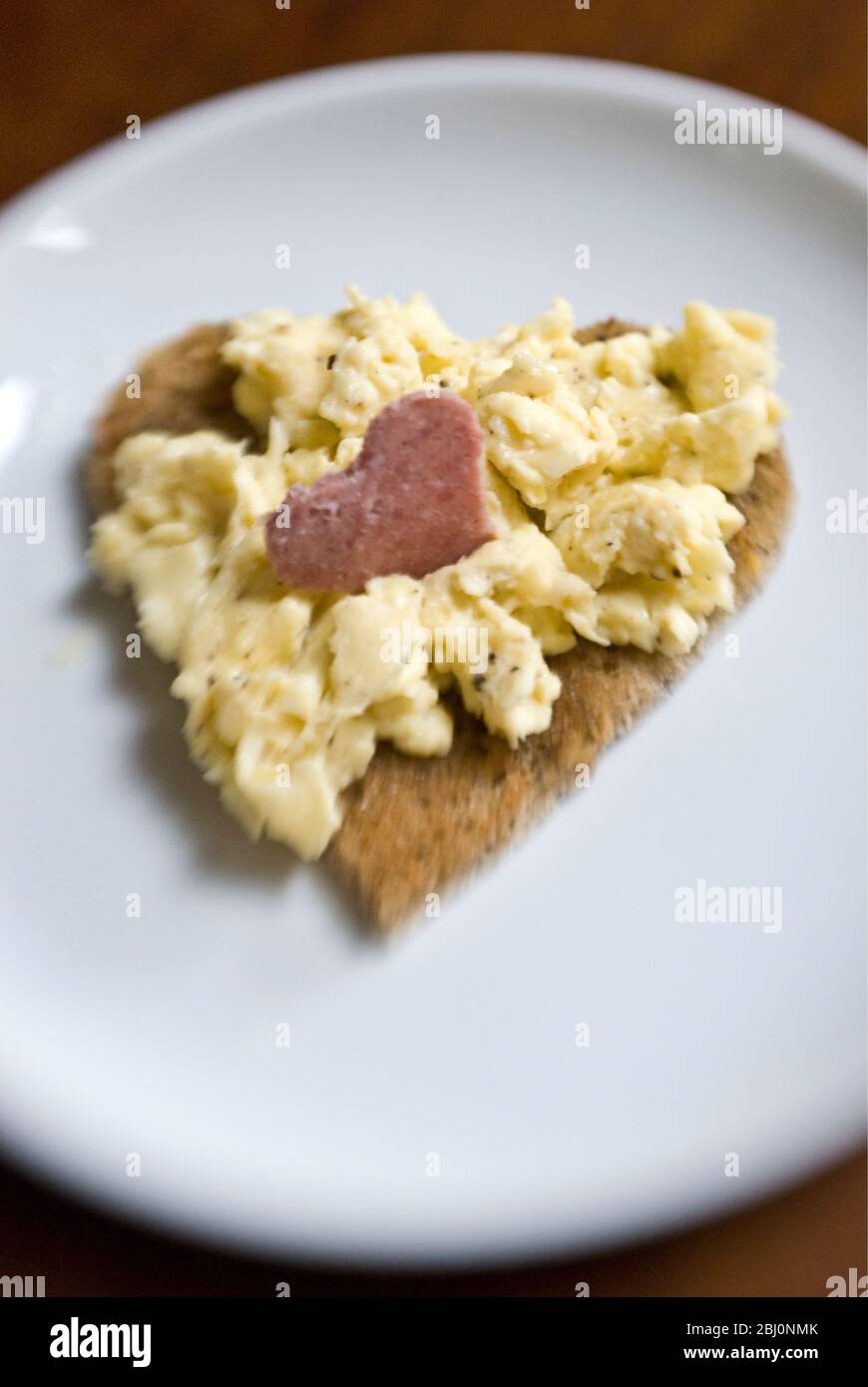 Valentinstag Frühstück mit Rührei auf herzförmigem Toast mit Salami in Herzform geschnitten - Stockfoto