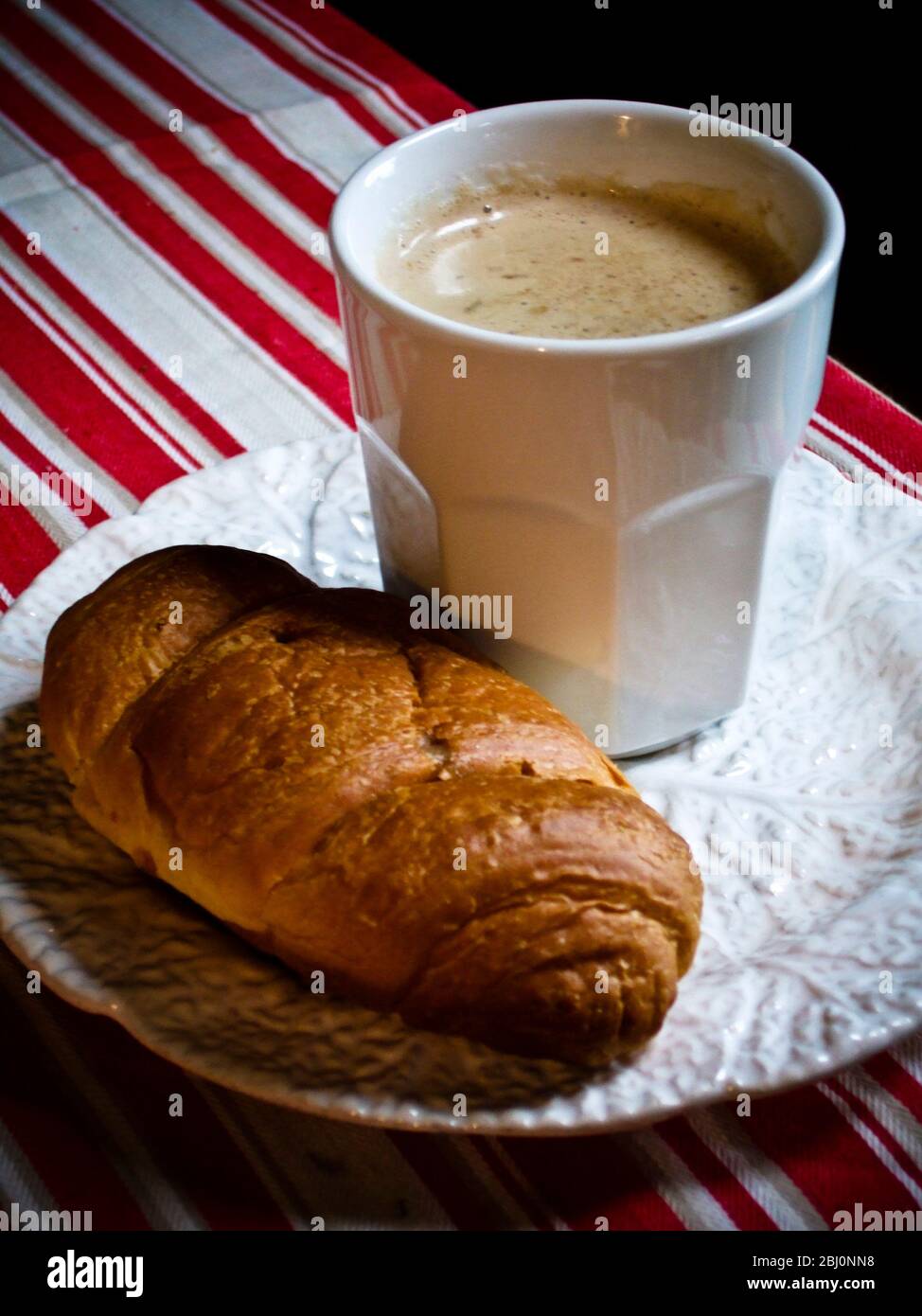 Weißer Becher Kaffee auf Teller mit Croissant - Stockfoto