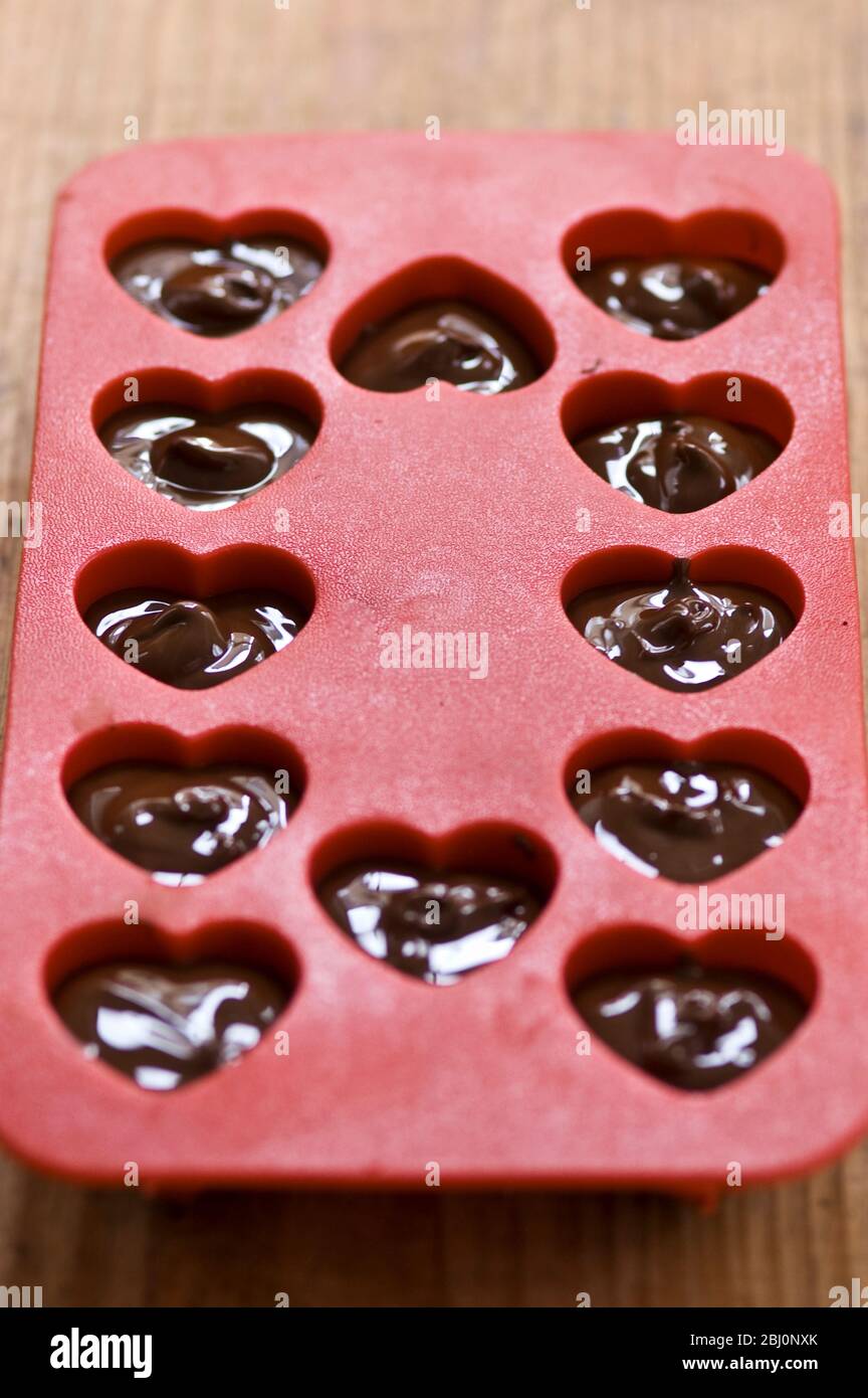 Herstellung Herz geformt in Schokolade für Valentinstag in roten Herz Form Form - Stockfoto