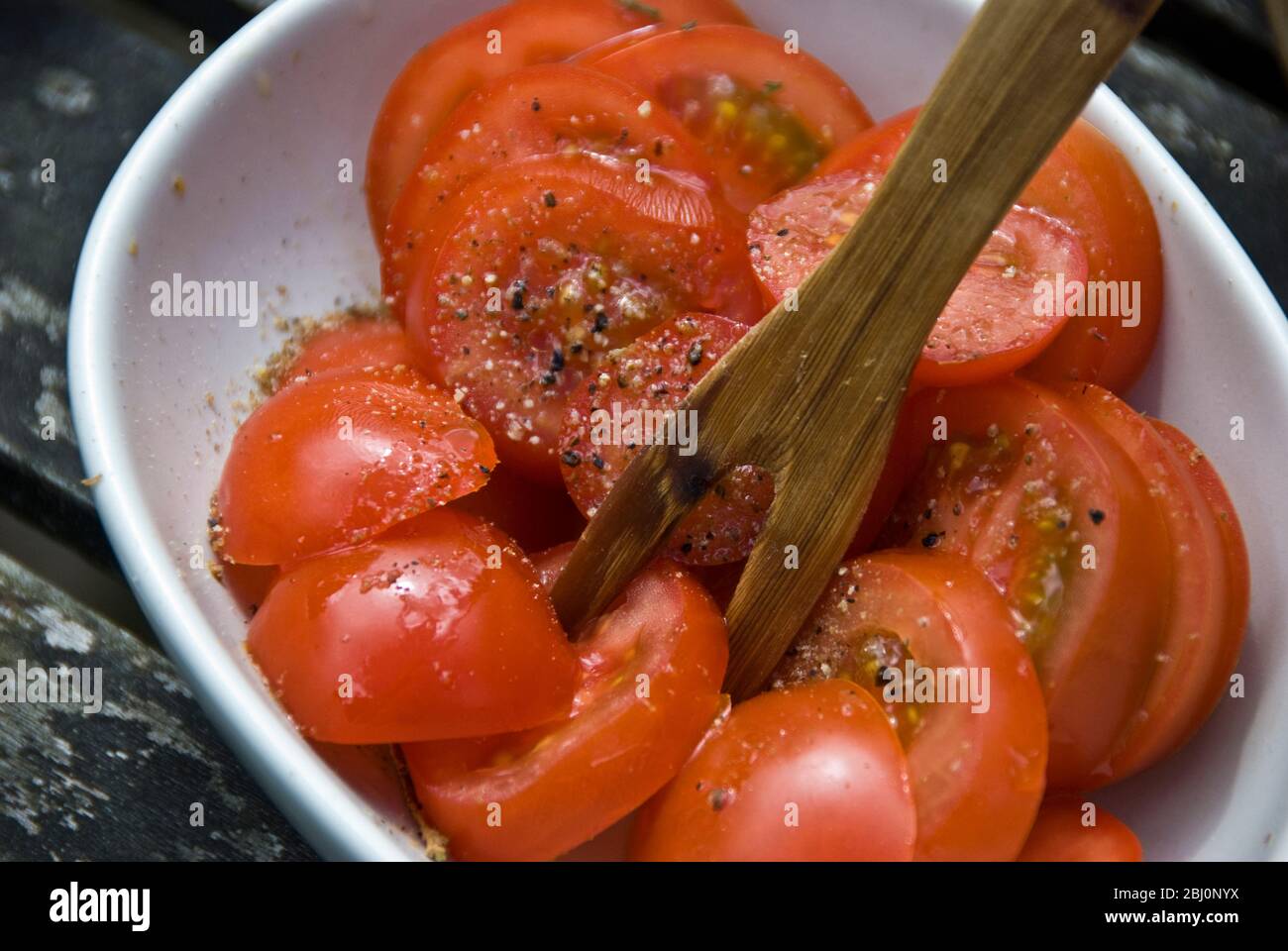 Einfacher Salat aus Kirschtomaten mit Olivenöl und Balckpepper in kleiner Schüssel mit Holzgabel - Stockfoto