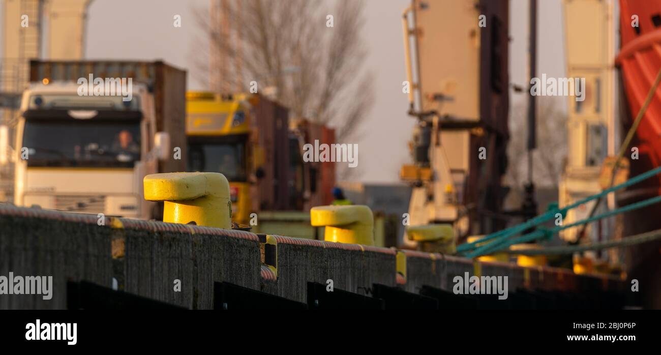 LKW warten auf Containerverladung am Hafenquai, geringe Schärfentiefe Stockfoto