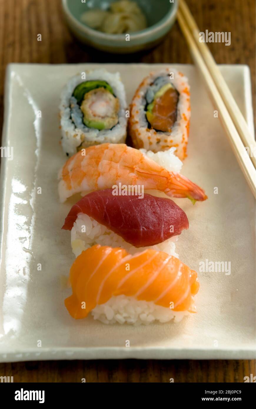 Teller mit japanischen Sushi-Stücken mit Essstäbchen und Schüssel mit Wasabi und Soja - Stockfoto