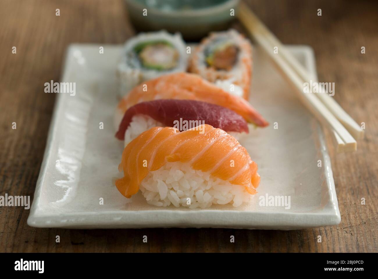 Teller mit japanischen Sushi-Stücken mit Essstäbchen und Schüssel mit Wasabi und Soja - Stockfoto