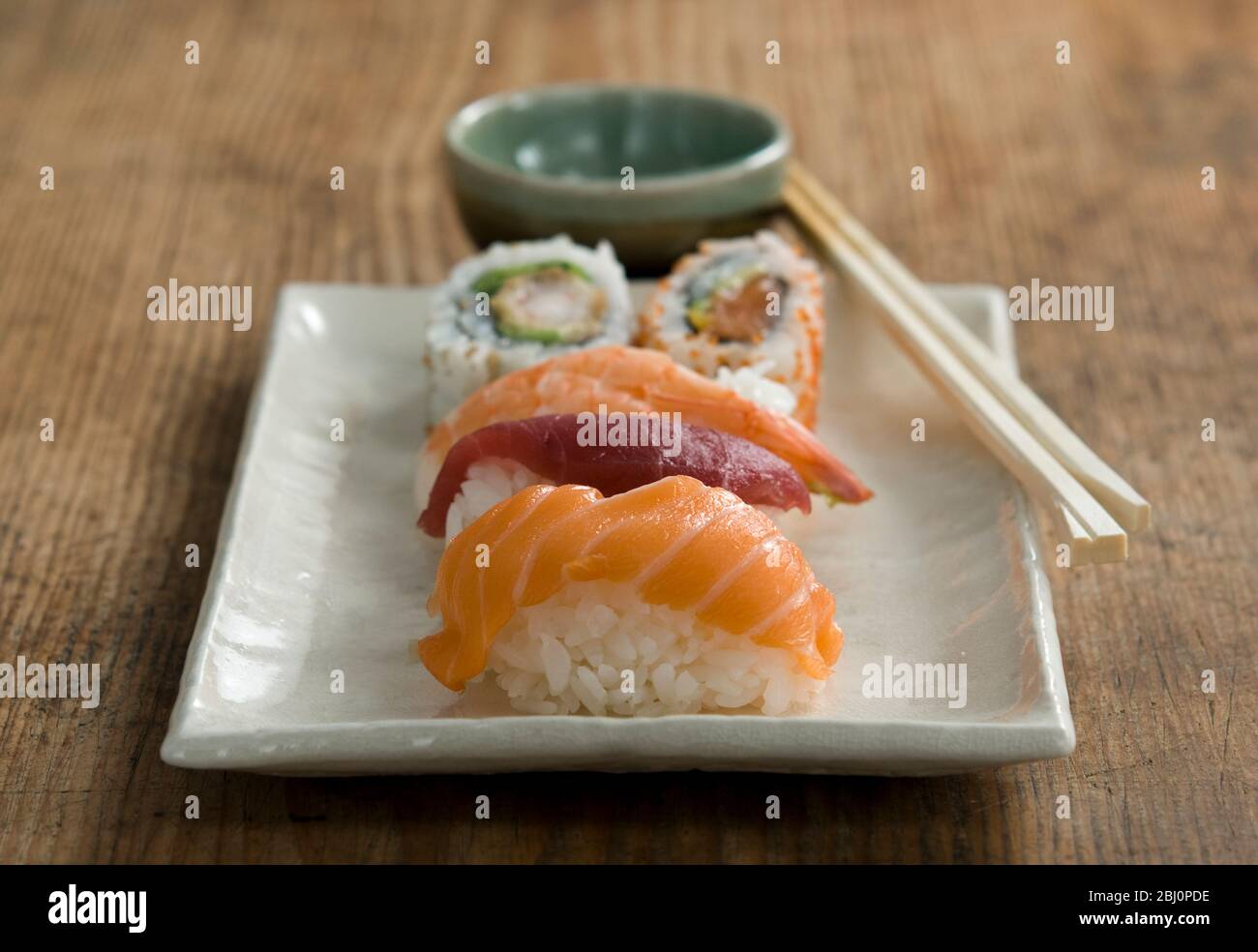 Teller mit japanischen Sushi-Stücken mit Essstäbchen und Schüssel mit Wasabi und Soja - Stockfoto