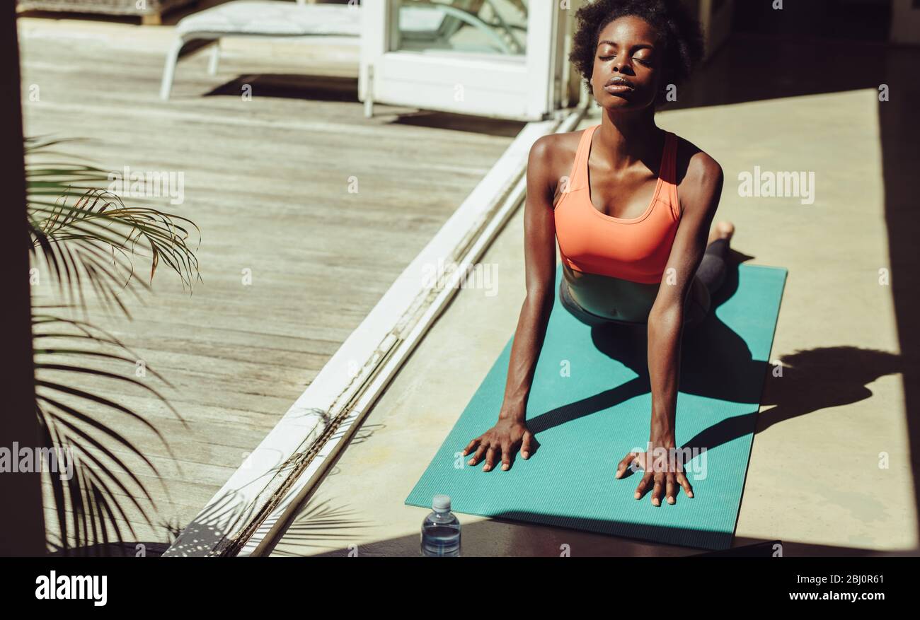 Gesunde Frau, die zu Hause auf Yogamatte trainiert. Fitness Frau Yoga zu üben, um fit zu bleiben. Weibliche in Cobra Yoga Pose am Pool. Stockfoto