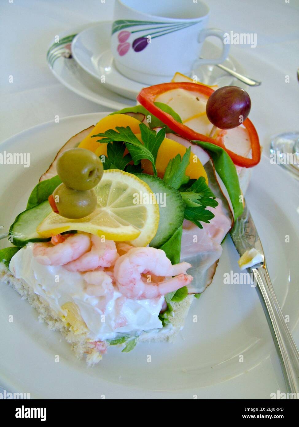 Ein schwedisches offenes Sandwich wird als eine leichte Mahlzeit an einer Rezeption serviert. Sie beginnen an einem Ende mit der Garnelen-Mayonnaise, arbeiten durch den Schinken und Salat, so Stockfoto
