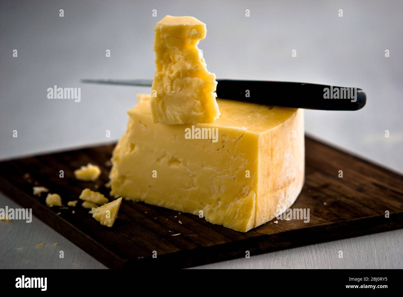 Keil Cheddar-Käse, auf Holzkäseplatte geschnitten - Stockfoto