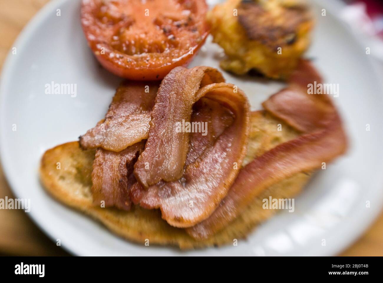 Warmes Frühstück mit gegrilltem Speck, Tomaten, potao Kuchen und gebratenem Brot - Stockfoto