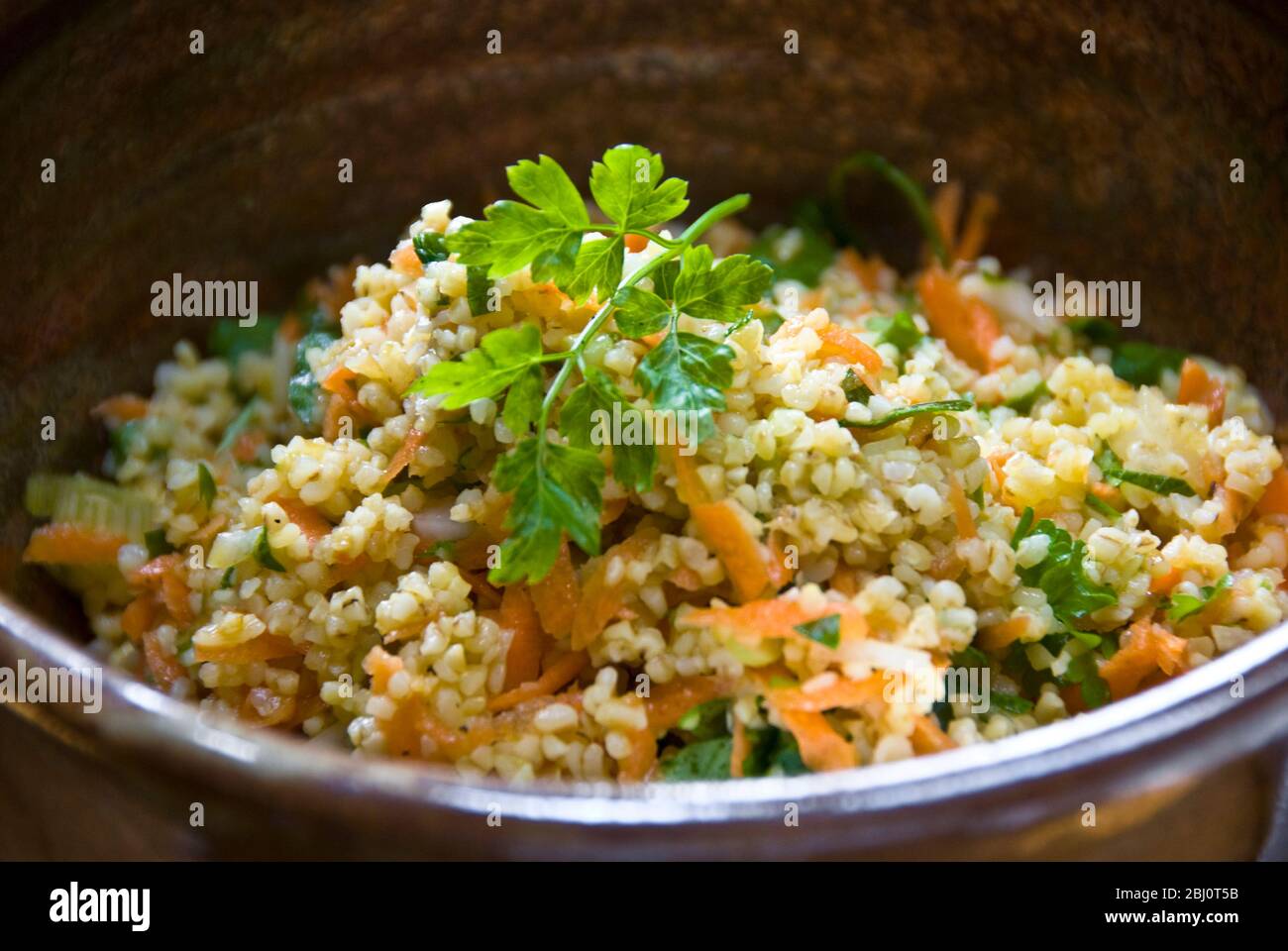 Gesunde Mittagszeit Salat aus Burghulweizen mit geriebener Karotte, Zitronensaft, Olivenöl, gehackte Gurke und Petersilie. - Stockfoto