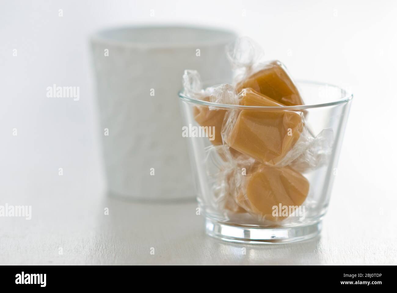 Ein paar Toffees in Cellophan in einem Glastopf gewickelt - Stockfoto