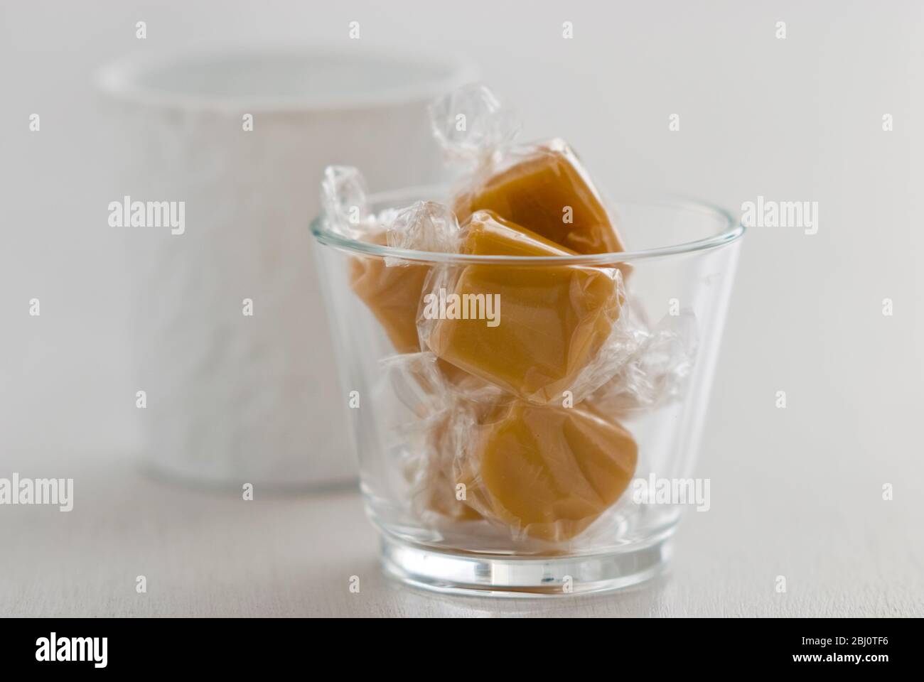 Ein paar Toffees in Cellophan in einem Glastopf gewickelt - Stockfoto