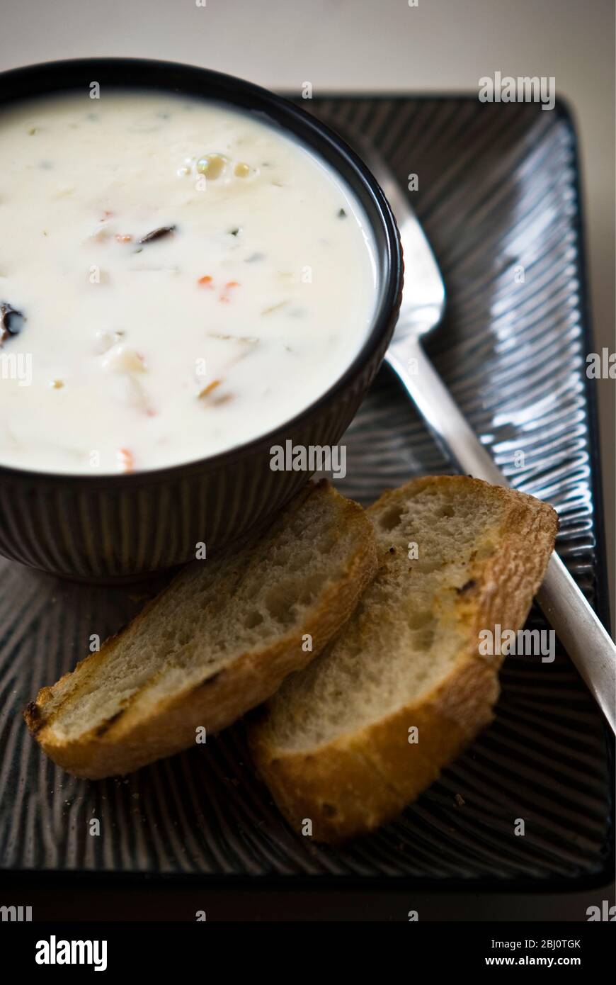 Muschel, Meeresfrüchte und geräucherter Lachs-Chowder in Töpferschüssel mit gegrilltem Brot - Stockfoto