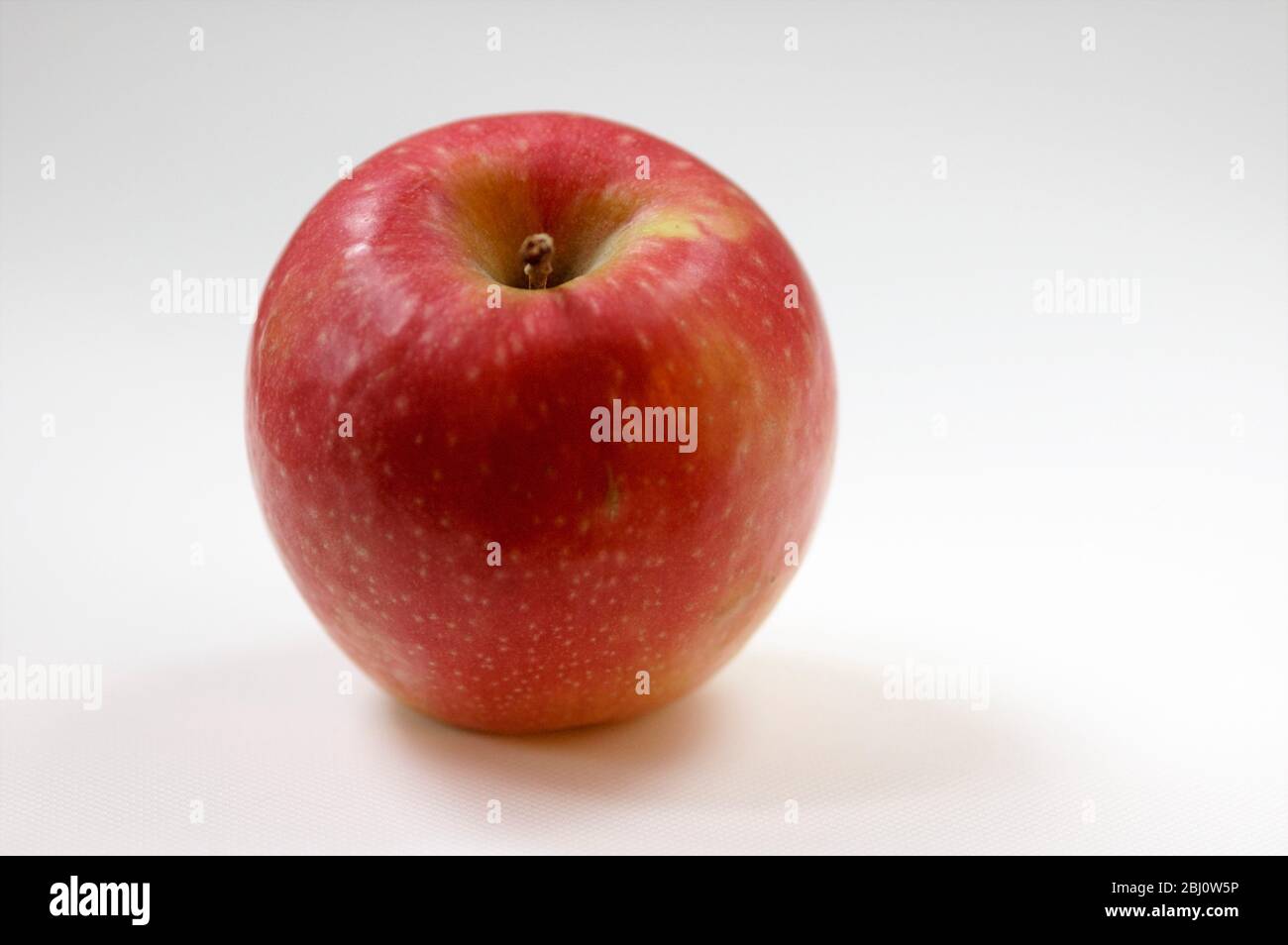 Einzelner glänzender roter Apfel auf weißem Hintergrund - Stockfoto